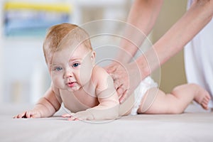 Mother massaging baby in bed at home