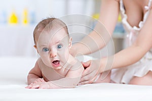 Mother massaging baby in bed at home