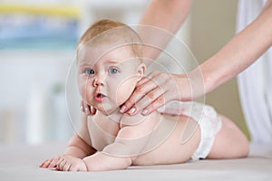 Mother massaging baby in bed at home