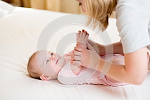 Mother massaging or doing gymnastics baby girl