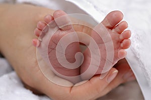 Mother massaging the feet of her newborn baby