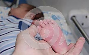 Mother massaging little newborn baby foot relaxing