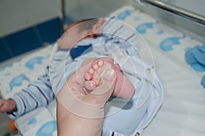 Mother massaging little newborn baby foot relaxing