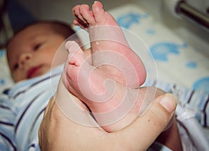 Mother massaging little newborn baby foot relaxing