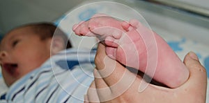 Mother massaging little newborn baby foot relaxing