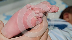 Mother massaging little newborn baby foot relaxing