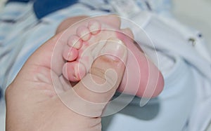 Mother massaging little newborn baby foot relaxing