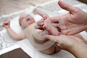 Mother massaging the newborn boy foot