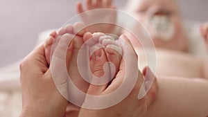 Mother massaging and tickling small baby feet. close up slow motion shot