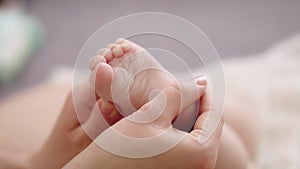 Mother massaging and tickling small baby feet. close up slow motion shot