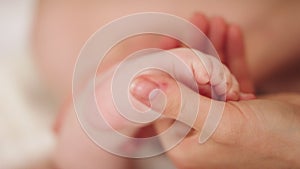 Mother massaging and tickling small baby feet. close up slow motion shot