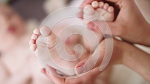 Mother massaging and tickling small baby feet. close up slow motion shot