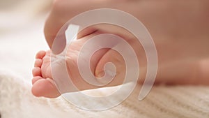 Mother massaging and tickling small baby feet. close up slow motion shot