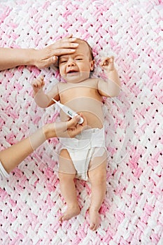 Mother measuring temperature of crying baby