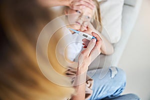 Mother measuring temperature of her ill kid