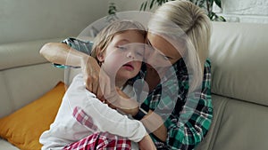 Mother measuring temperature of her ill kid at background. Sick child with high fever lying at sofa at home