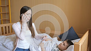 Mother measuring temperature of her ill kid and calling a doctor