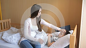 Mother measuring temperature of her ill kid. Sick child with high fever lying at bad at home