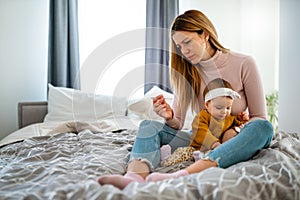 Mother measuring temperature of her ill kid. Sick child with high fever, mother holding thermometer.