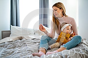 Mother measuring temperature of her ill kid. Sick child with high fever, mother holding thermometer.