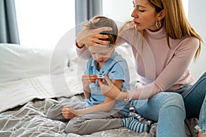 Mother measuring temperature of her ill kid. Sick child with high fever, mother holding thermometer.