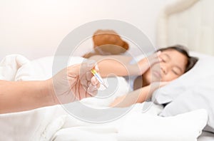 Mother measuring temperature of her ill kid from thermometer.