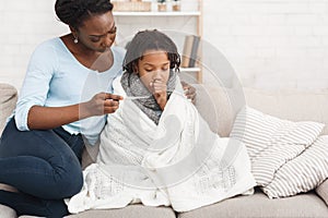 Mother measuring temperature of her sick daughter with thermometer