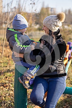 Mother - a middle-aged young brunette woman plays with her three-year-old son on a sunny autumn day. Cheerful mood, smiles