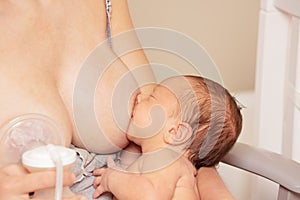 Mother multitasking using breast pump and breastfeed photo