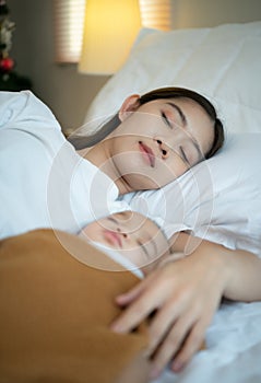 A mother must sleep and rest with her newborn baby. In the white bedroom, warm sunlight in the evening of the day