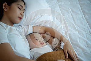 A mother must sleep and rest with her newborn baby. In the white bedroom, warm sunlight in the evening of the day