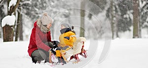 Mother/nanny talk with small child during sledding in winter park photo