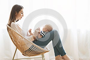 Mother with newborn baby on lap sitting in woven chair