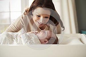 Mother With Newborn Baby Lying On Changing Table In Nursery