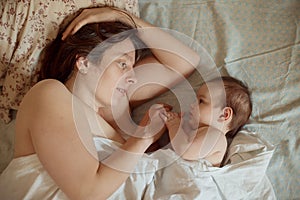 Mother and newborn baby sleeping in bed. Mother kissing baby`s head. Motherhood concept.