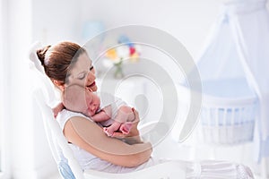 Mother and newborn baby in white nursery