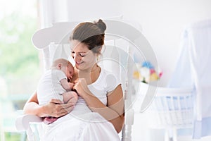 Mother and newborn baby in white nursery