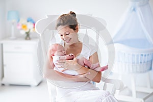 Mother and newborn baby in white nursery