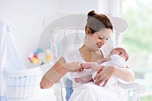 Mother and newborn baby in white nursery