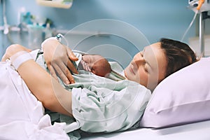 Child birth in maternity hospital. Mother and newborn. Young mom hugging her newborn baby after delivery. Woman giving birth