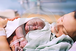 Child birth in maternity hospital. Mother and newborn. Young mom hugging her newborn baby after delivery. Woman giving birth