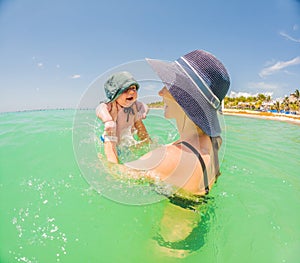 Mother and newborn son share a serene swim in the sea, creating timeless memories by the water& x27;s embrace