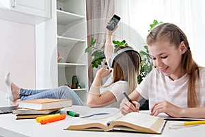 Mother is not helping daughter to do homework while using her smart phone and listening to music with headphones