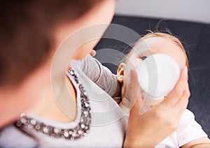 Mother nourishiing baby with milk bottle.