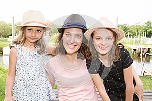 Mother outdoor nportrait with two girls daughter with straw hat near lake river in spring photo