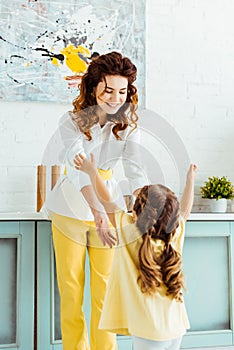 Mother outstretching hands to daughter in kitchen