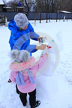 Mother painting snowman. Enjoying winter holidays. Winter family vacations