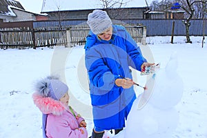 Mother painting snowman. Enjoying winter holidays. Winter family vacations