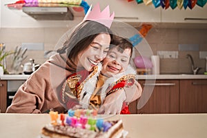 Mother in paper crown embracing her son with Down syndrome