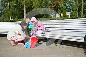 Mother in the Park on the bench puts children on his feet roller